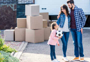 young happy family standing together in front of new house