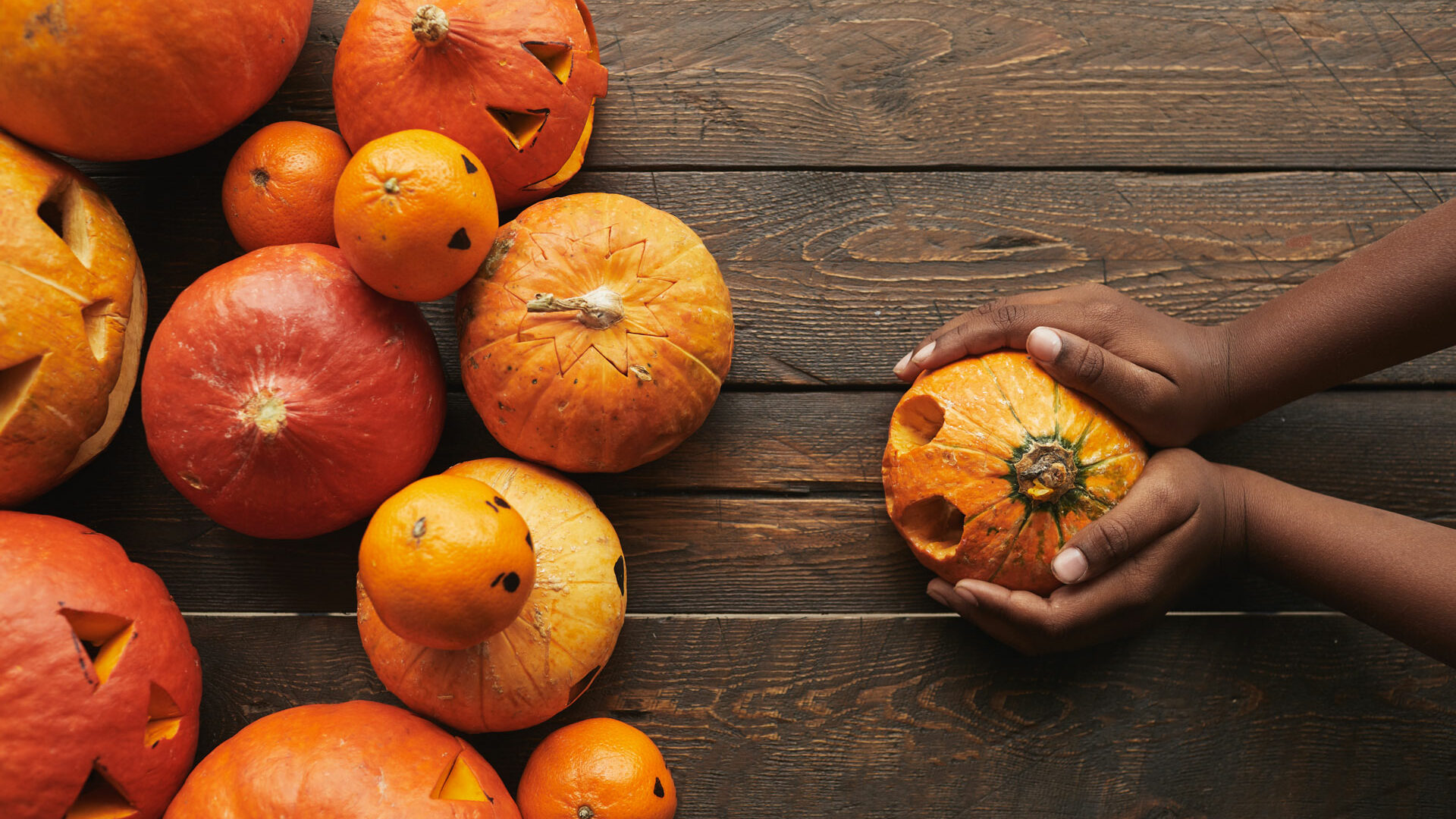 Pumpkins on table with a hands holding one pumpkin