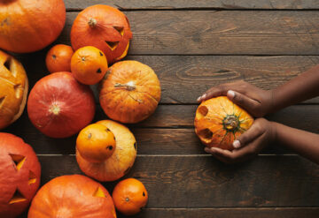 Pumpkins on table with a hands holding one pumpkin